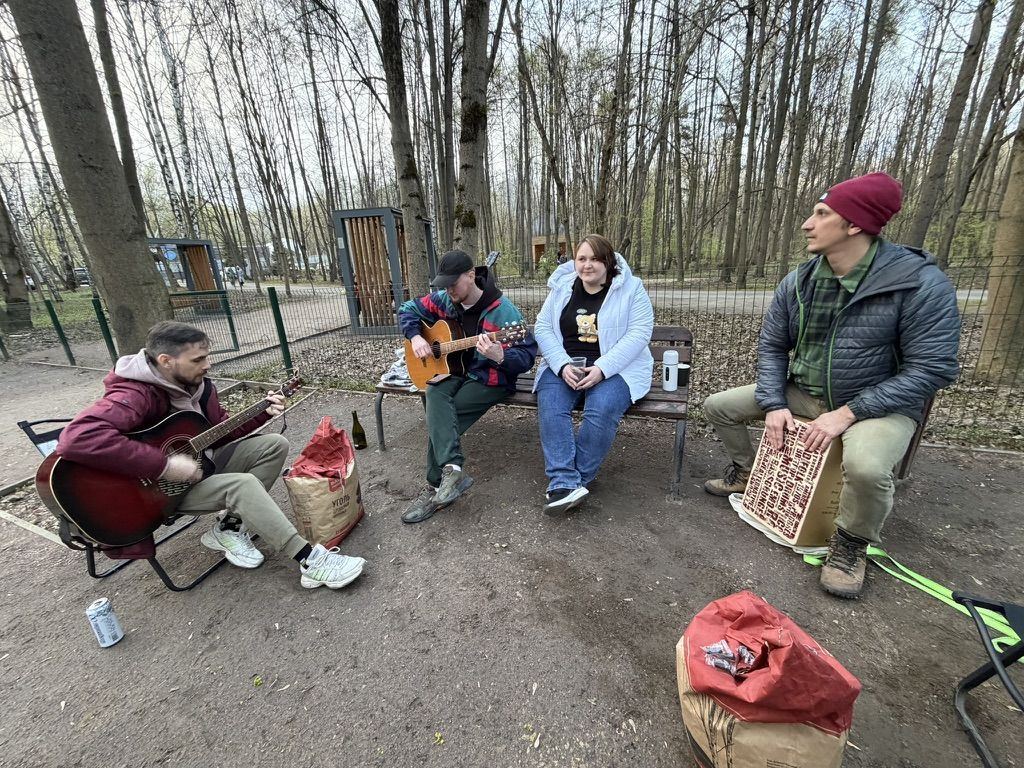 Компания на весеннем пикнике играет на гитарах и кахоне в парке